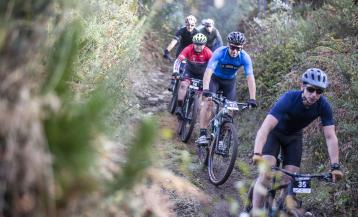 Un grupo de participantes pedaleando por un camino forestal de Carballo