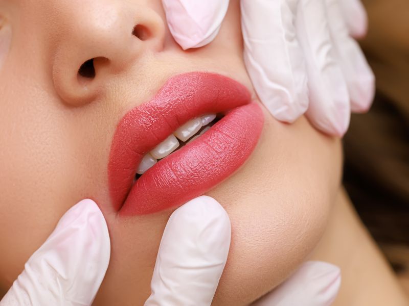 Labios chic joven modelo que realiza maquillaje labial permanente maestro estira labios modelo dedos