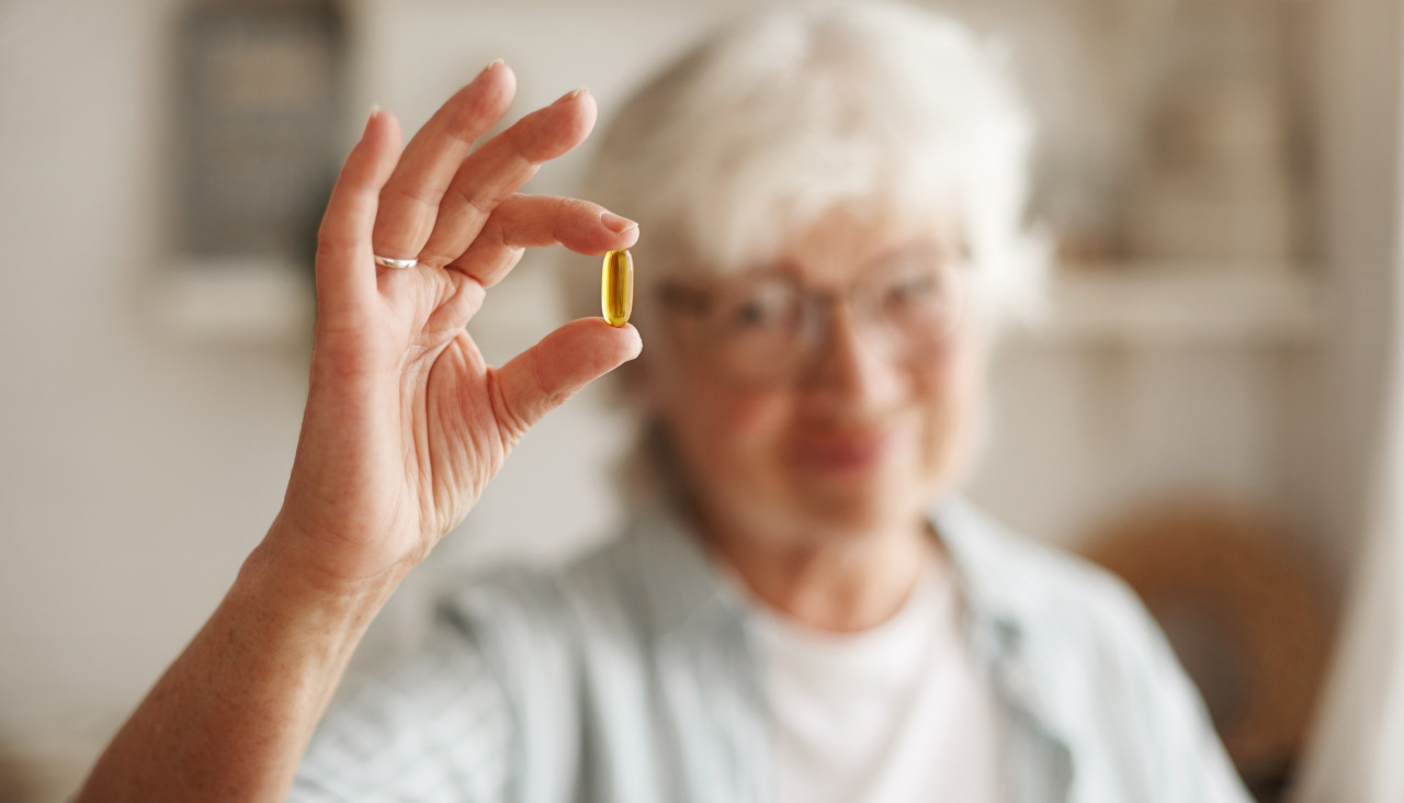 Concepto de alimentacion nutricion dieta y salud primer plano de la mano de una anciana con aceite de pescado o suplemento de acidos grasos poliinsaturados omega 3 en forma de capsula que va tomar uno durante el almuerzo