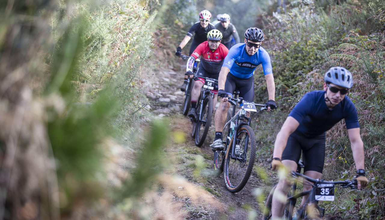 Un grupo de participantes pedaleando por un camino forestal de Carballo
