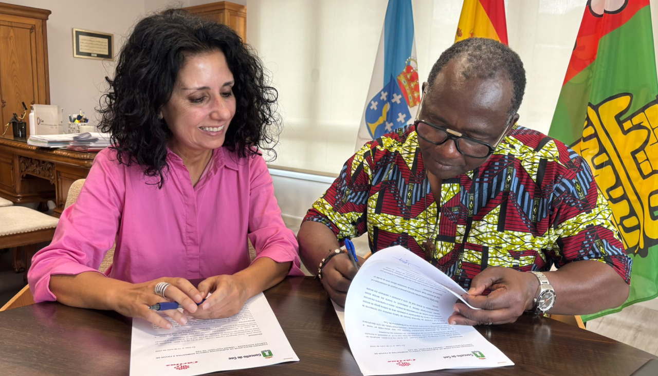 La alcaldesa ceense, Margarita Lamela, y el párroco  Desire Kouakou Tanoh, firmando el acuerdo