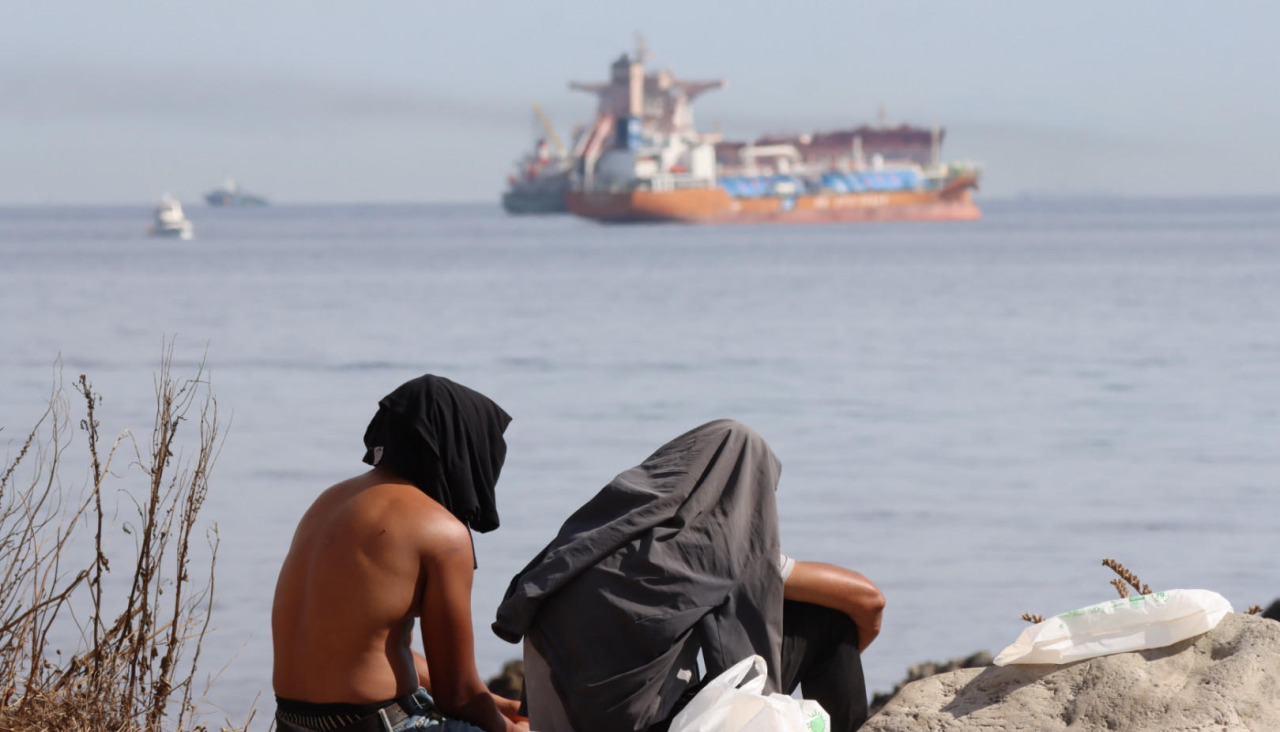 CEUTA, 29/08/2026.- Migrantes en la playa de El Trampolín de Ceuta este sábado, un día después de que centenares de personas volvieran a salir a las calles en Ceuta en una nueva marcha para protestar por la situación en la que la entrada de miles de migrantes el pasado 30 de julio ha sumido a esta ciudad autónoma española, y reclamar al Gobierno que adopte medidas. EFE/ Reduan